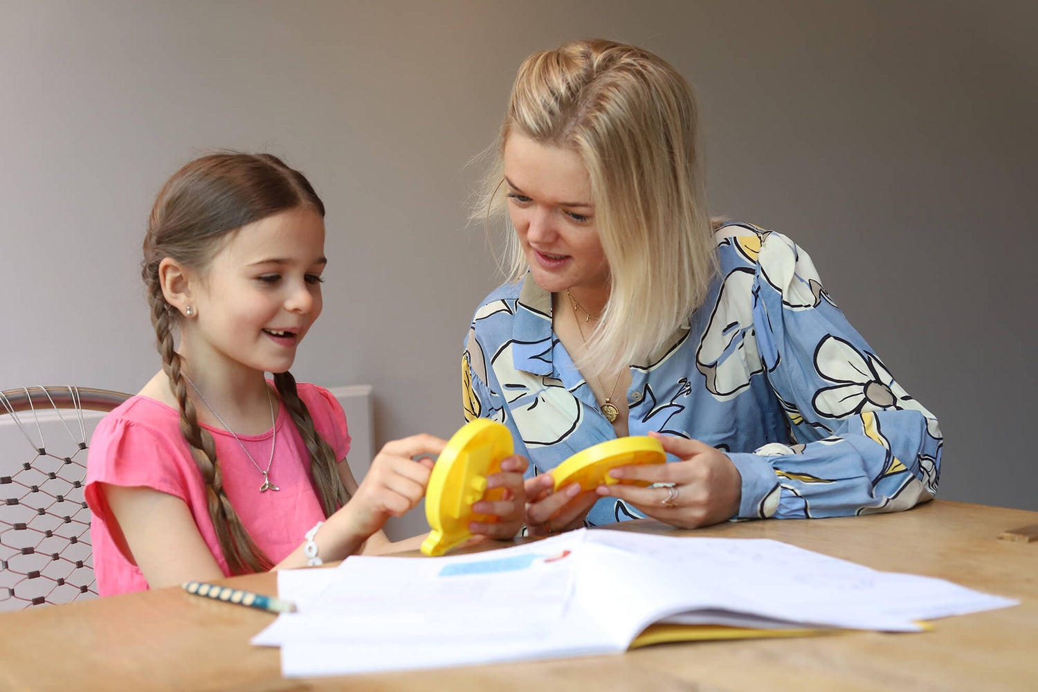 Phoebe tutoring a female student using 2 clocks to show how to tell the time