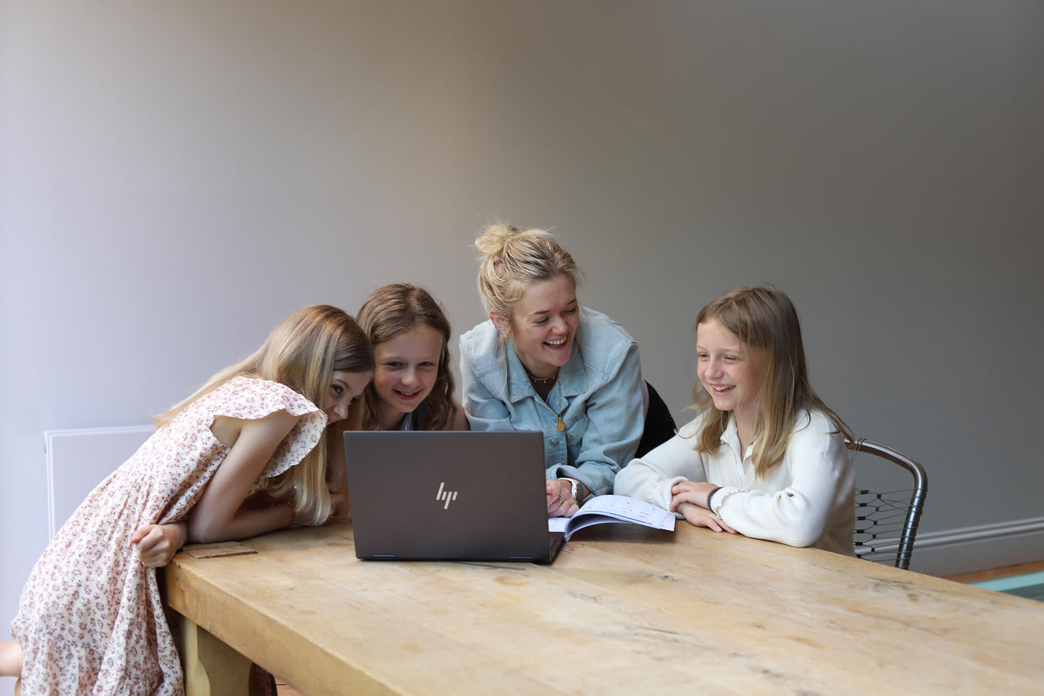Phoebe and 3 young girls working from a textbook with a laptop