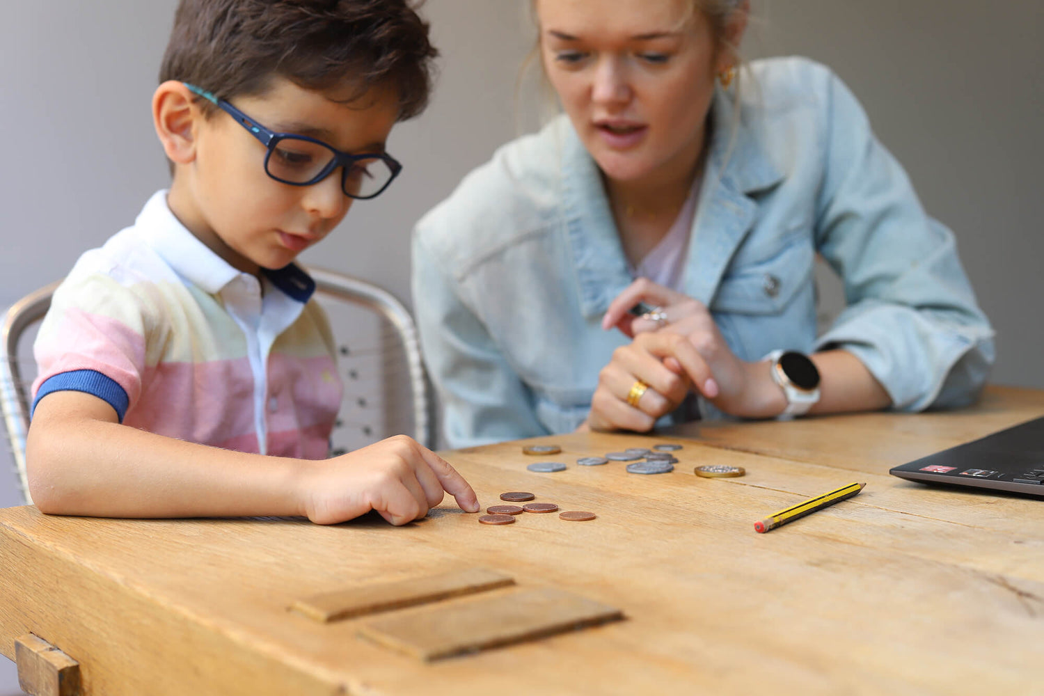 Phoebe tutoring a young boy in glasses counting coins